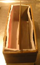 Al molde que vamos a utilizar le hemos puesto en la parte central y longitudinalmente un trozo de cartón unos milímetros más largo que el molde para que se sujete bien y no se mueva al añadir el jabón.